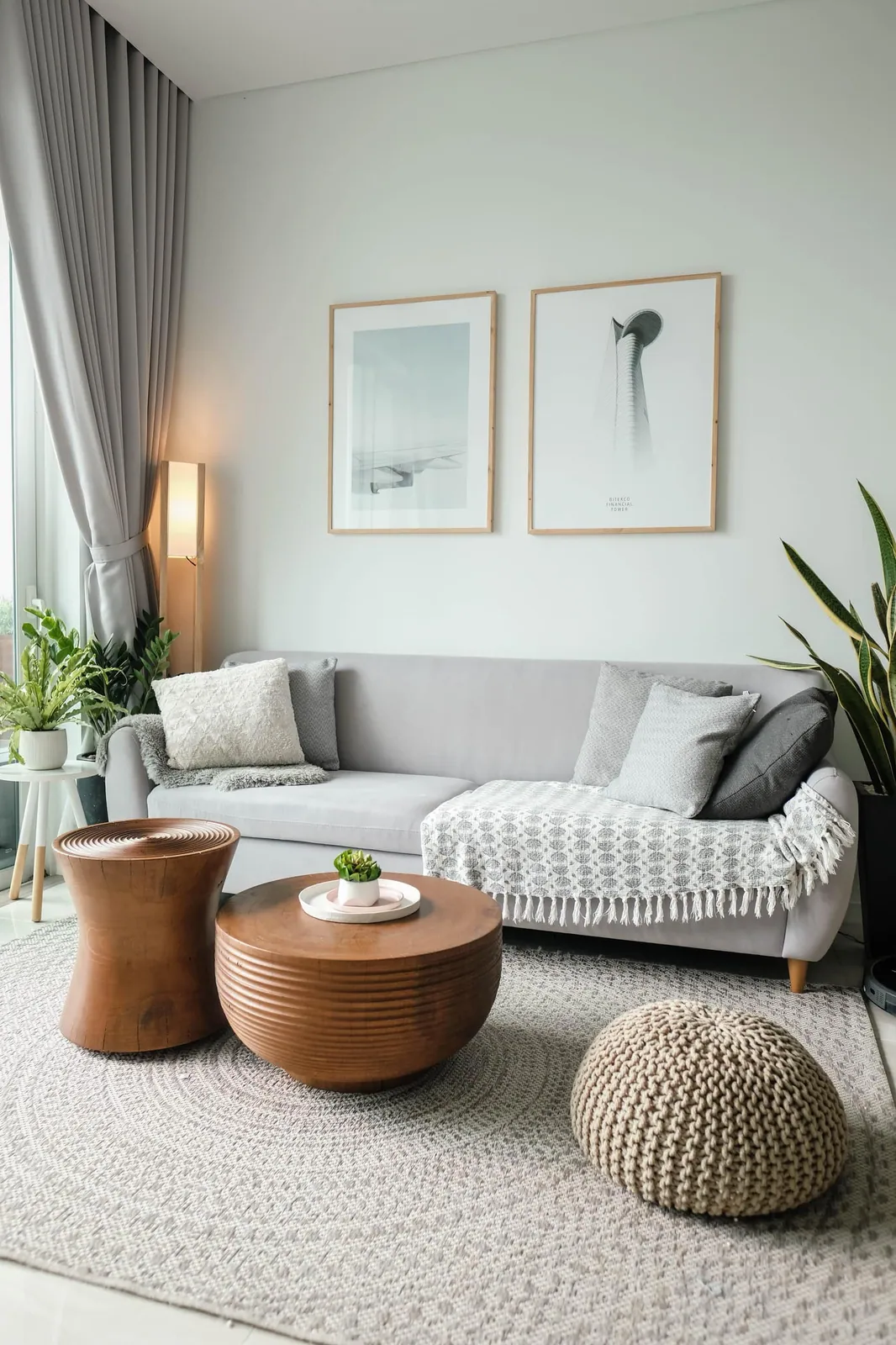 Helles Therapiezimmer mit grauem Sofa, Holztischen und Pflanzen.